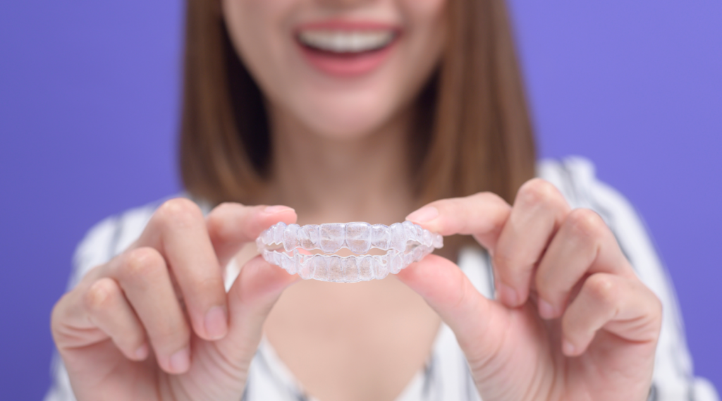 a girl holding Invisible Clear Aligners in her hand